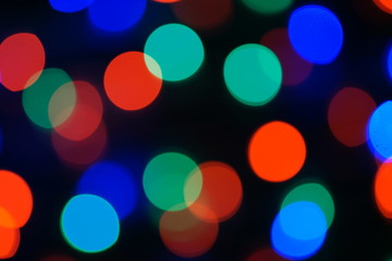 Multi-color blue holiday garland. Garland is blurred. Many big colorful round lights. Fully defocused photo. Blurred background and foreground. Holiday mood. New Year and Christmas is coming.