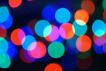 Multi-color blue holiday garland. Garland is blurred. Many big colorful round lights. Fully defocused photo. Blurred background and foreground. Holiday mood. New Year and Christmas is coming.