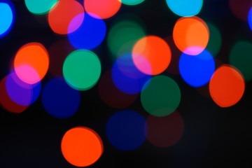 Multi-color blue holiday garland. Garland is blurred. Many big colorful round lights. Fully defocused photo. Blurred background and foreground. Holiday mood. New Year and Christmas is coming.