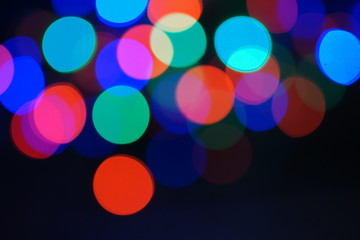 Multi-color blue holiday garland. Garland is blurred. Many big colorful round lights. Fully defocused photo. Blurred background and foreground. Holiday mood. New Year and Christmas is coming.