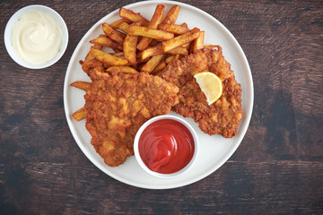 Original Schnitzel mit Ketchup und Zitrone vom Kalb top view closeup 