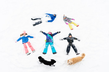 Group of children and dogs play in snow