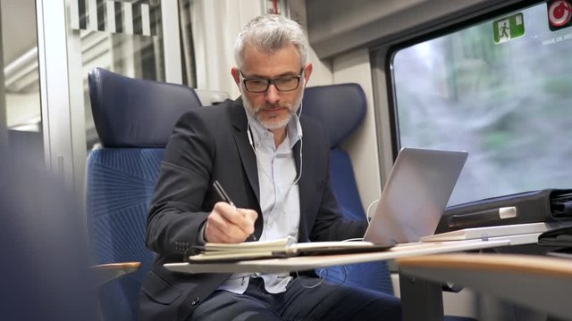 Businessman going to work by train, talking on phone