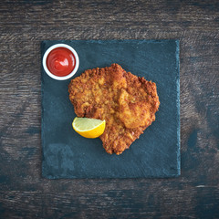 Original Schnitzel mit Ketchup auf Schiefertafel top view closeup 
