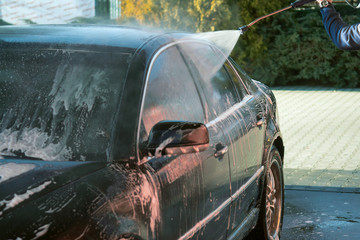 Car wash high-pressure apparatus of water. Black car on a handwash self-service.