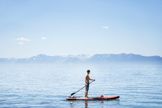 Side view of shirtless man paddleboarding in lake