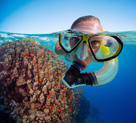 Under and above water view of woman snorkeling.