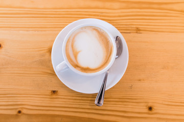 A white cup.of capuccino on wooden table