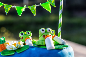 A blue birthday cake with green frogs figures