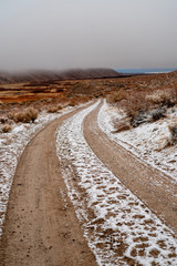 tire tracks in snow on brown desert road in Eastern Sierra Nevada mountain valley winter landscape in California