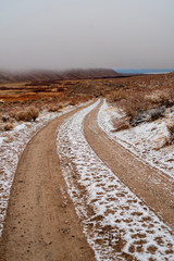 tire tracks in snow on brown desert road in Eastern Sierra Nevada mountain valley winter landscape in California