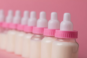 Baby bottle full of milk on a pink background