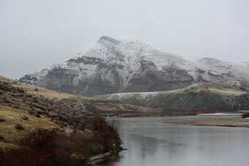 white capped mountain with a river in the foreground