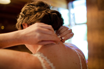 Rear view of bride wearing necklace while standing at home