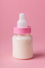 Baby bottle full of milk on a pink background
