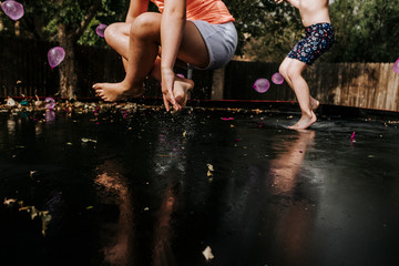 Low section of playful sisters jumping on trampoline