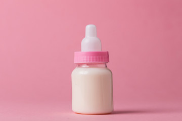 Baby bottle full of milk on a pink background