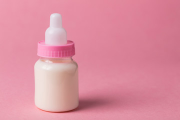 Baby bottle full of milk on a pink background