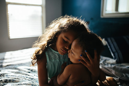 Sister embracing brother on bed at home