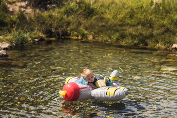 Boy lying on inflatable airplane in lake during summer