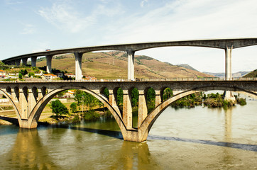 big historical bridge over Duoro river in Regua region vineyards, Portugal