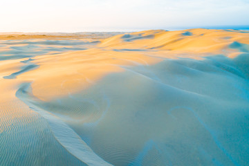 Aerial view of beautiful pristine sand dunes with ripples at sunset
