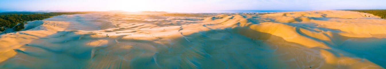 Wide aerial panorama of Anna Bay sand dunes at sunrise with one person. Anna Bay, New South Wales, Australia