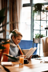 Young businesswoman relaxing on coffee break and reading newspaper.