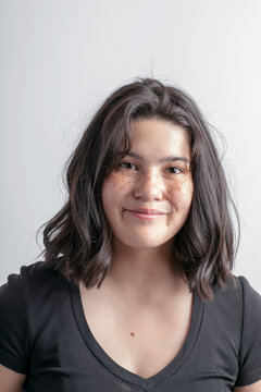 Portrait of smiling teenage girl sitting against white background