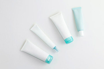 Set of blank white and turquoise blue cosmetics containers on light background. Copy space. Flat lay.