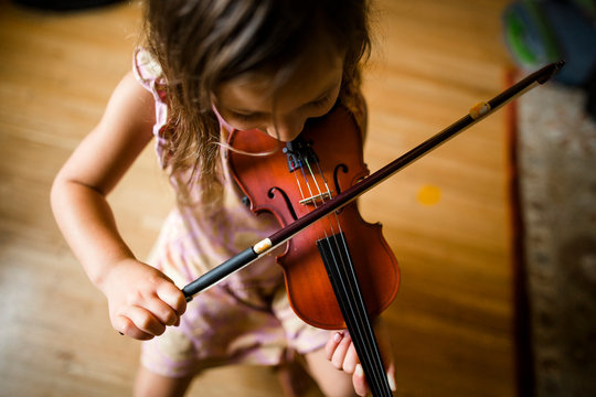 High angle view of girl playing violin while sitting at home