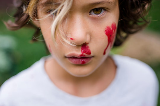 Close-up portrait of cute boy with red face paint standing in park