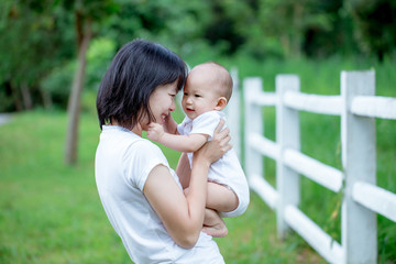 Fototapeta premium Asian mother carrying her baby boy. Smiling and fun together.