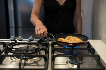 Young woman cooking french bread in frying pan