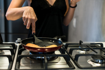 Young woman making french bread in frying pan