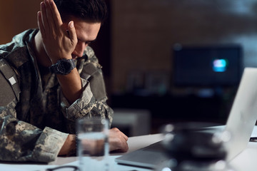 Upset military officer crying while having video call on laptop.