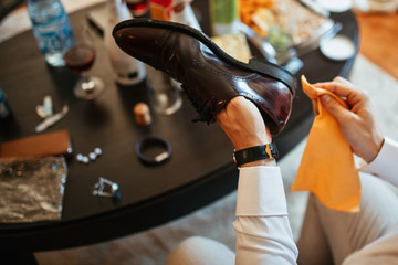 Close up of groom cleaning his shoes before wedding ceremony.