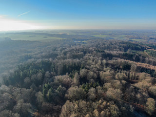 Aerial view of countryside landscape with forests and farmlands during beautiful winter day in the morning. Belgium, Walloon Brabant