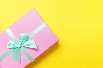 Christmas New Year birthday valentine celebration present romantic concept. Gift box wrapped pink paper isolated on yellow colourful trendy modern fashion background. Flat lay top view copy space