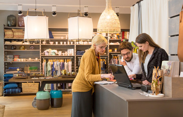 Co-workers small business owners and employees working meeting using laptop computer in retail shop store