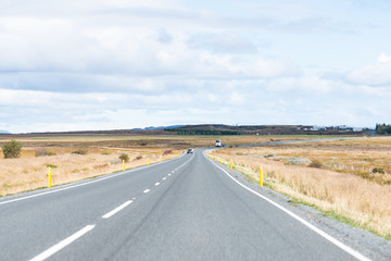 Vew of road trip car and truck on ring road near golden circle on cloudy autumn day in South Iceland on route 1 and dry field meadow