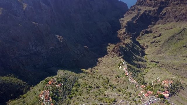 The small road in the center of the mountain ranges in Tenerife Spain with the tall mountains on the side