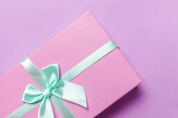 Christmas New Year birthday valentine celebration present romantic concept. Small gift box wrapped pink paper isolated on purple violet pastel colorful trendy background. Flat lay top view copy space