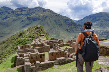 Fototapeta na wymiar Tourist exploring the Inca Trails leading to the ruins of Pisac, Sacred Valley, major travel destination in Cusco region, Peru. Vacations and adventures in South America.