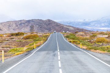 Landscape view of Thingvellir mountains with clouds covering on golden circle in Iceland during day and highway 37 or 365 in autumn with cars on road