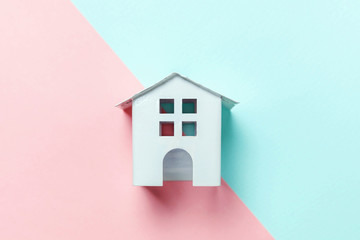 Simply design with miniature white toy house isolated on blue pink pastel colorful trendy geometric background. Mortgage property insurance dream home concept. Flat lay top view copy space