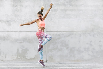 Tancerz w odzieży sportowej mody skoki na szarej ścianie - 250550721