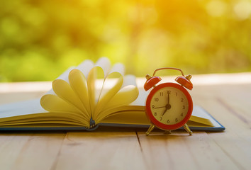 Alarm clock with book on nature background