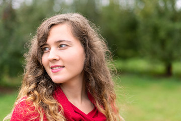 Apple orchard with many green trees park in garden bokeh background during autumn fall in farm countryside of Virginia with young happy woman in red dress portrait smiling