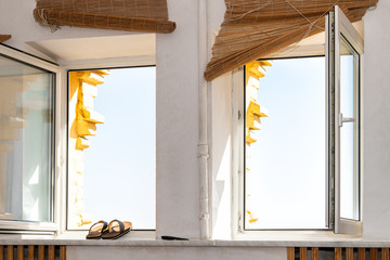 View of bright sky through two windows in vintage Kyiv or Kiev apartment flat with open glass window interior on sunny summer day and flip flop sandal shoes drying on windowsill